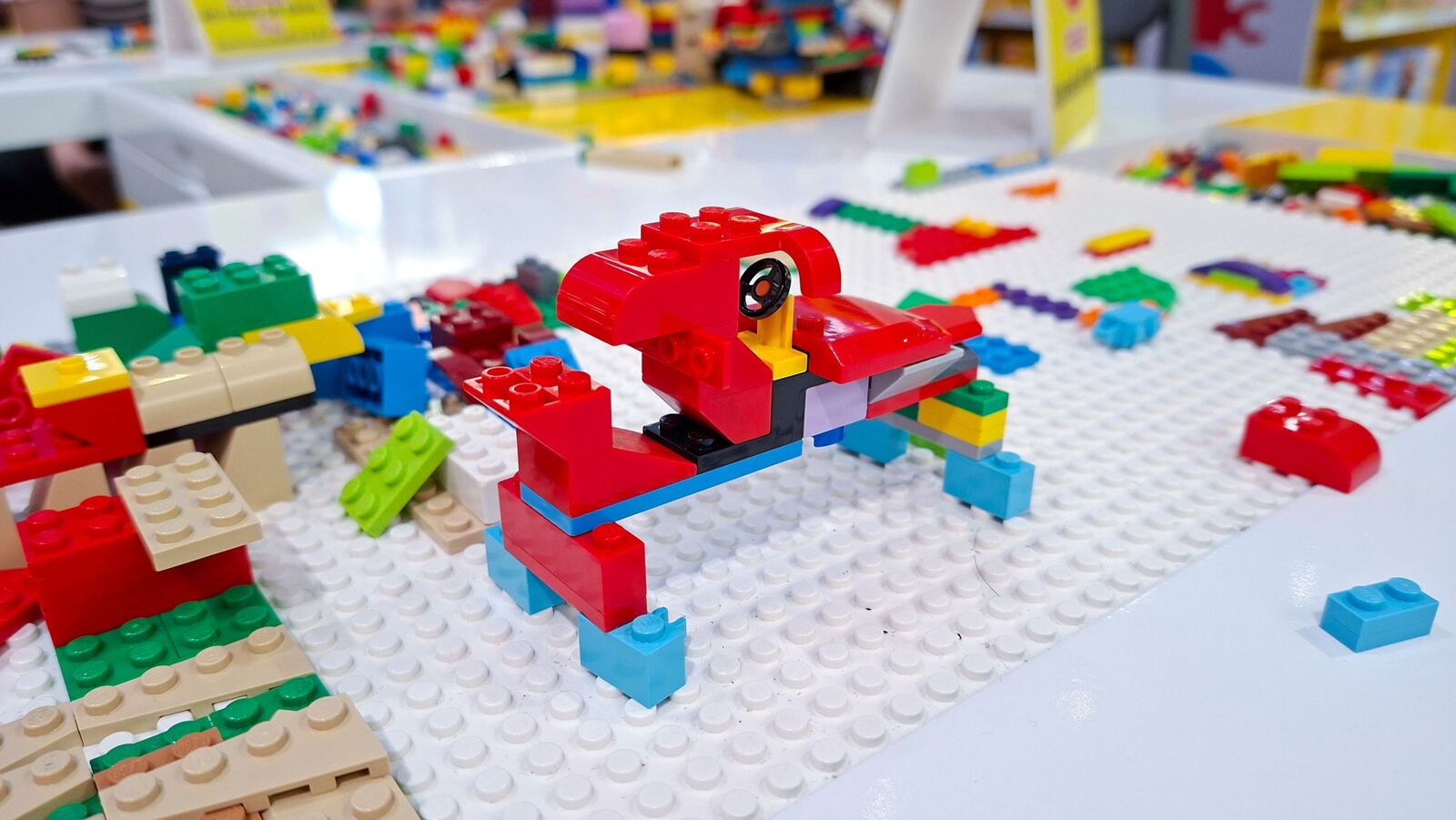 Modelo de ladrillos rojos y azules sobre una placa blanca rodeado de piezas sueltas en la mesa de un taller LEGO SERIOUS PLAY